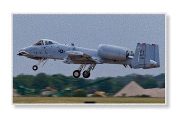 A gray A-10 Thunderbolt II military aircraft takes off from a runway with its landing gear still extended.