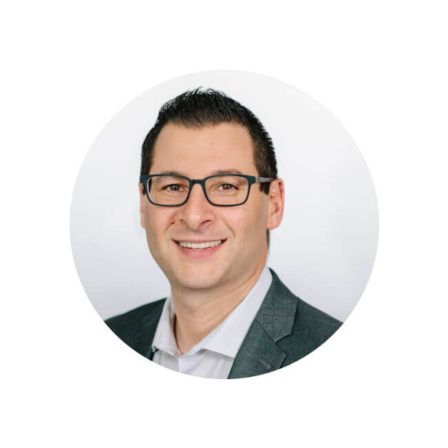 Professional headshot of Andrew Weitz smiling, wearing glasses, a gray blazer, and a white open-collar shirt.