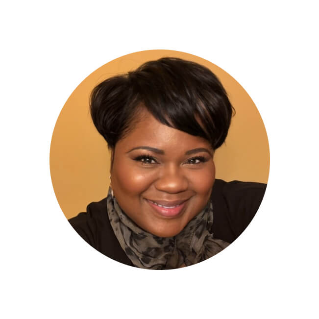 Professional headshot of Daphne, a smiling woman with short dark hair, hoop earrings, and a patterned scarf.