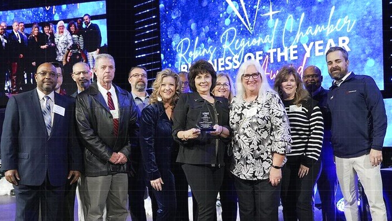 Credence team members pose on stage with a trophy at the Robins Regional Chamber Business of the Year Awards ceremony.