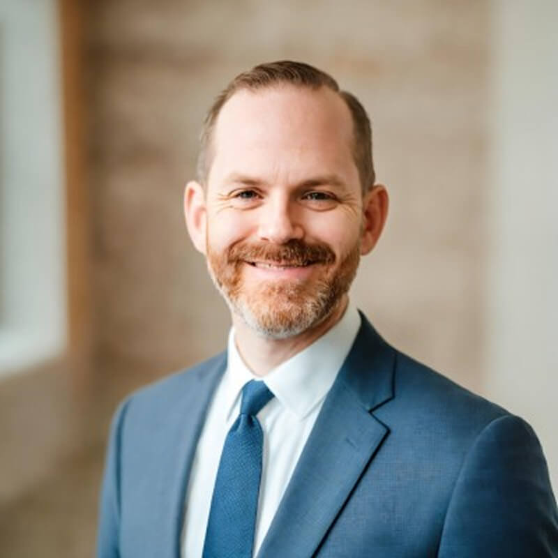 Credence Our Team Kaleb Johnson Image Kaleb Johnson smiling in a professional headshot, wearing a blue suit and tie with a neatly trimmed beard.