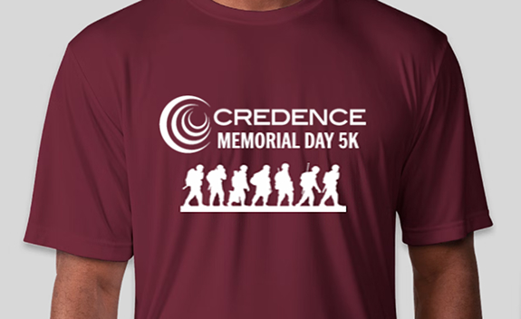 A maroon t-shirt featuring the Credence Memorial Day 5K logo with white silhouettes of soldiers and runners beneath it.
